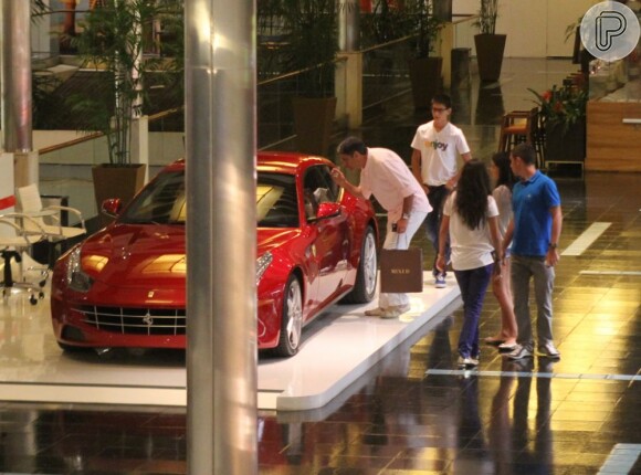 William Bonner e seus filhos admiram a Ferrari vermelha em exposição