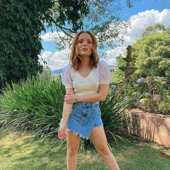 Larissa Manoela combinou saia jeans assimétrica, tênis e blusa com manga bufante