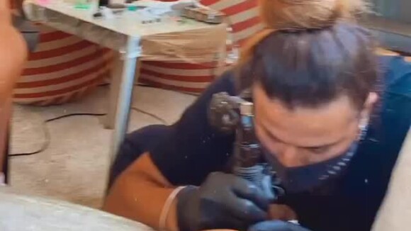 Anitta exibe duas tatuadoras em cada perna, ao mesmo tempo