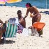 Viviane Araujo passa bronzeador no namorado em dia de praia
