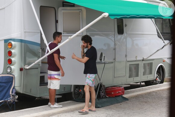Chay Suede conversa com integrante da equipe de produção antes de gravar comercial na praia de São Conrado