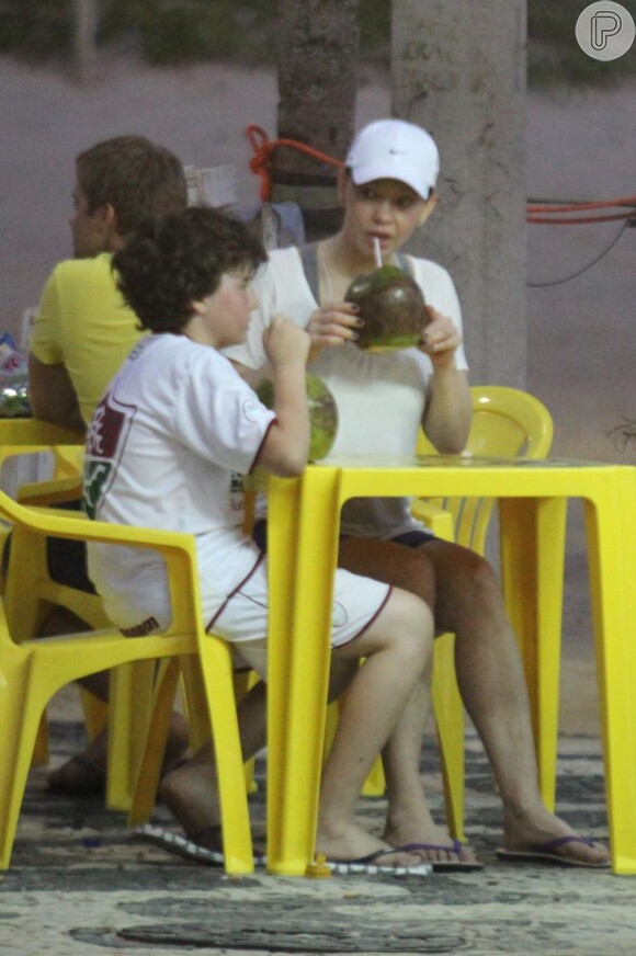 Em dia de sol no Rio, Julia Lemmertz bebe água de coco com o filho, Miguel, em Ipanema, em outubro de 2012