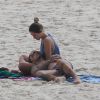 Também fofos, Felipe Titto e a mulher, Mel Martinez, namoram discretamente na praia da Barra da Tijuca. O casal trocou carinhos nas areias
