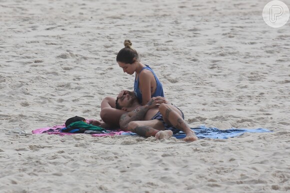 Também fofos, Felipe Titto e a mulher, Mel Martinez, namoram discretamente na praia da Barra da Tijuca. O casal trocou carinhos nas areias