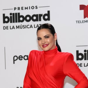 Maite Perroni usou um vestido vermelho longo com fenda e salto alto preto para evento de música