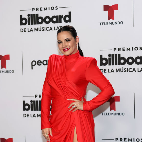 Maite Perroni usou um vestido vermelho longo com fenda e salto alto preto para evento de música