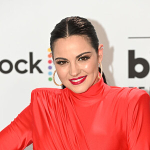 Maite Perroni combinou o look com vestido vermelho fechado com o cabelo preto e brincos de argola grandes