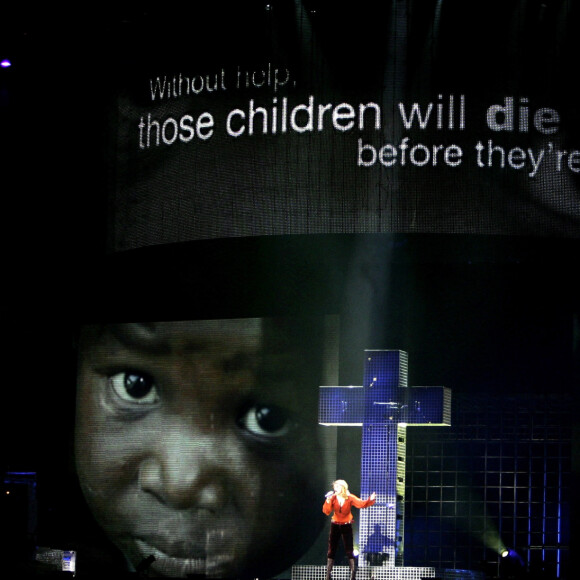 Madonna canta pendurada em uma cruz no show 'Confessions Tour' e chama atenção para a fome que afeta crianças em países da África. Veio a terceira excomunhão