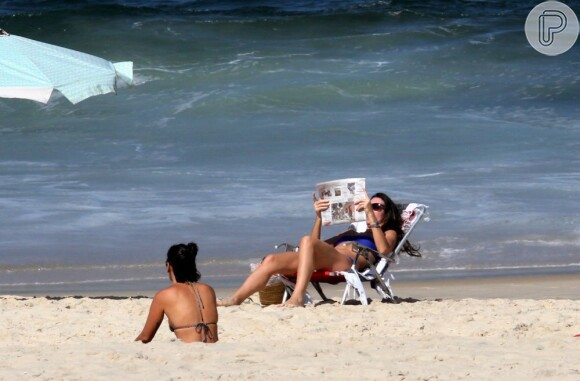 Glenda Koslowski lê jornal enquanto pega um solzinho na praia