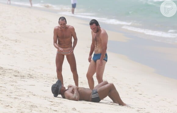 Rodrigo Lombardi exibe barriga tanquinho enquanto brinca com amigo na praia da Barra da Tijuca, no Rio