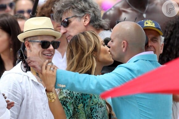 Jennifer Lopez é cumprimentada pelo rapper Pitbull. Logo atrás, de óculos e boné,  está Casper Smart, namorado da cantora