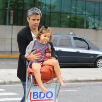 Otaviano Costa leva a filha, Olivia, no carrinho de bagagens em aeroporto do Rio