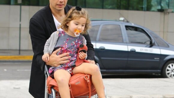 Otaviano Costa leva a filha, Olivia, no carrinho de bagagens em aeroporto do Rio