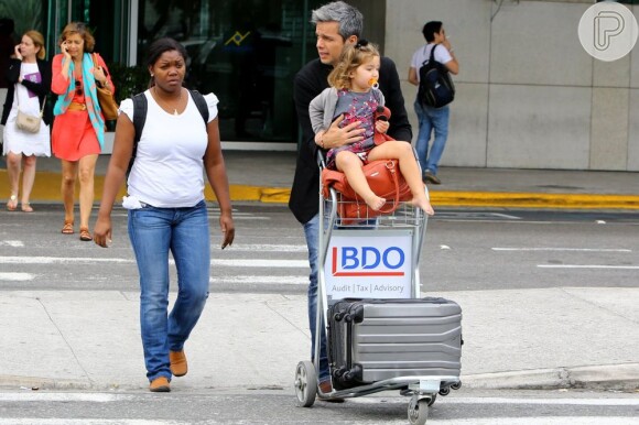 Otaviano Costa estava acompanhado da babá da filha e carregou a pequena no carrinho de bagagens ao deixar o aeroporto