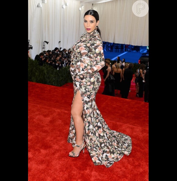 Kim kardashian posa com vestido florido segurando o barrigão de gravidez