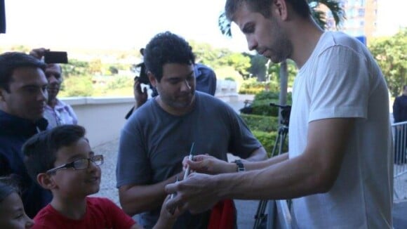 À espera de Shakira, Gerard Piqué distribui autógrafos em porta de hotel no Rio