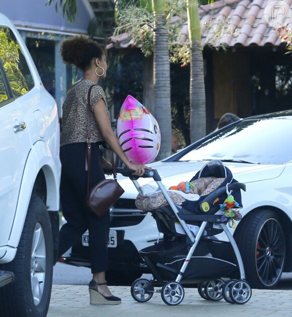 como boa mãe coruja, Taís Araújo empurra o carrinho da filha que tinha como adorno especial um balão da gatinha Hello Kitty