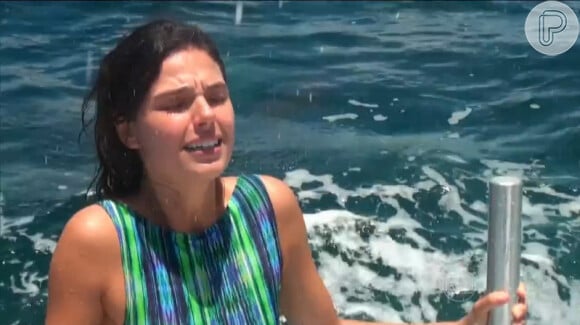 Isis Valverde faz careta ao colocar os pés no mar, lotado de tubarões