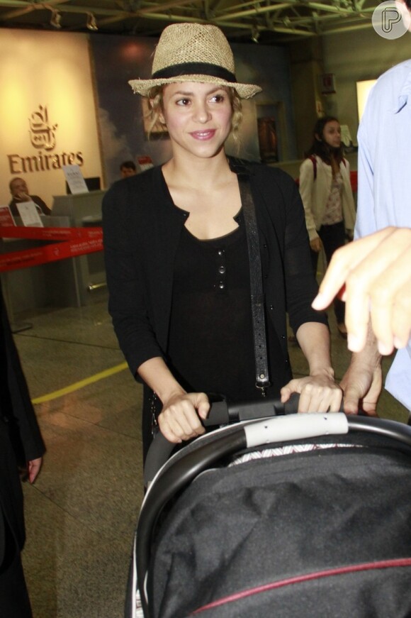 Shakira deixou o Brasil com o filho Milan usando uma roupa preta e chapéu de palha