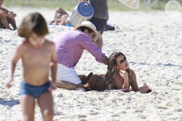 Caetano (Paulo Betti) passa óleo no corpo da namorada, Bernadete (Fernanda Souza) em cena de 'Malhação'