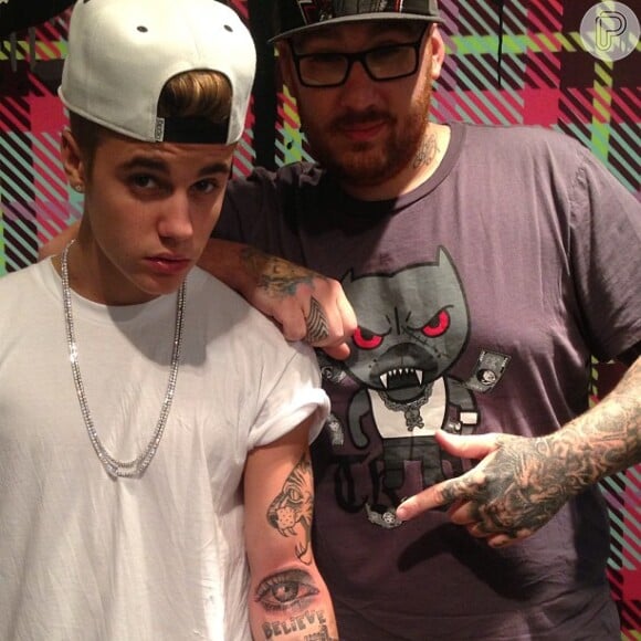 Justin Bieber exibe a tatuagem do olho da mãe que fez no braço esquerdo. O cantor teria cerca de mais de 15 tatuagens