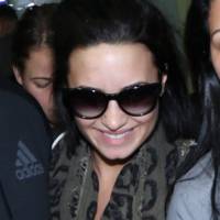 Demi Lovato desembarca no Brasil para show privado e tem bolsa puxada por fã