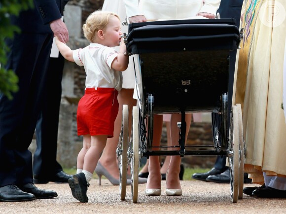 O príncipe George também roubou a cena em outro batizado. O herdeiro inglês ficou na ponta dos pés e se debruçou no carrinho para ver a irmãzinha, Charlotte Elizabeth Diana