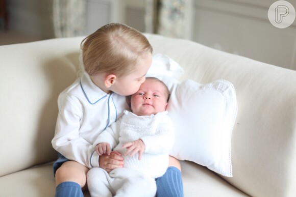 A princesa Charlotte Elizabeth Diana parece sorrir enquanto ganha um beijo do irmão mais velho, o príncipe George, nas primeiras fotos oficiais após seu nascimento