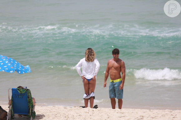 Ainda na areia, Deborah Secco mostrou boa forma com um biquíni de lacinho azul que estava por baixo da roupa, ao lado do marido, Hugo Moura