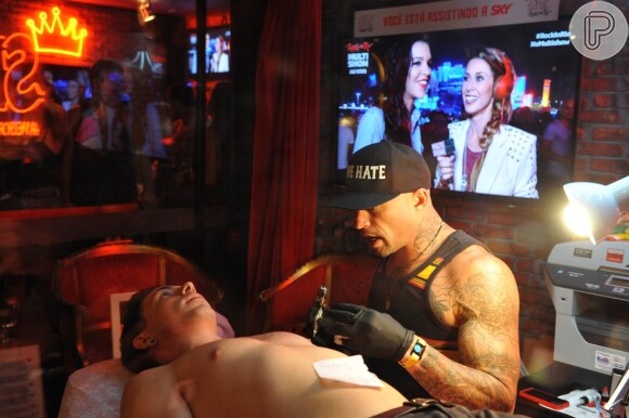 Mariana Rios aparece dando entrevista enquanto seu ex-noivo, Di Ferrero, se tatua, no Rock in Rio, em 20 de setembro de 2013