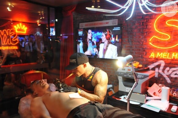 Di Ferrero é tatuado por Ami James, tatuador do 'Miami Ink' e 'NY Ink' com Mariana Rios ao fundo, no Rock in Rio