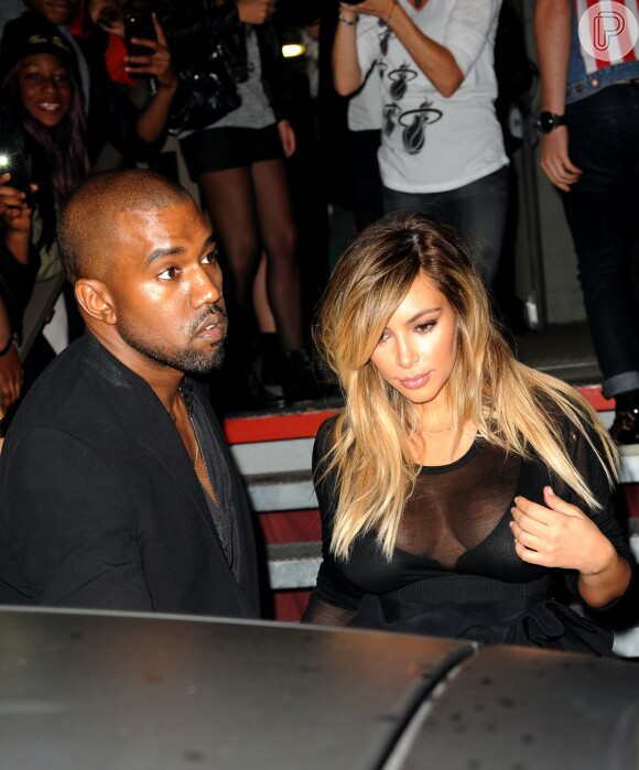 Kim Kardashian escolhe vestido com decote transparente para conferir o desfile da Givenchy na companhia do marido, Kanye West