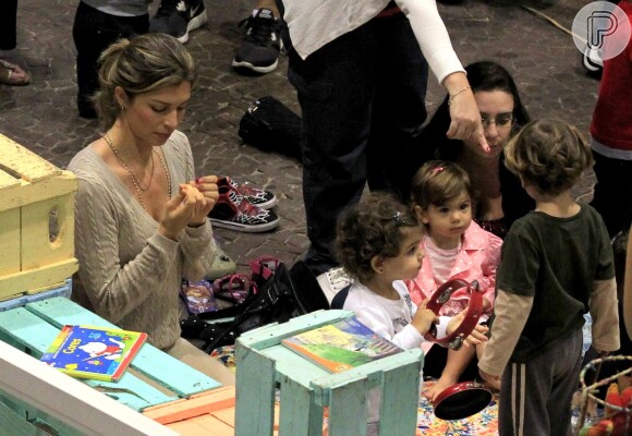 Grazi Massafera observa as unhas enquanto a sua filha, Sofia, brinca com os amiguinhos