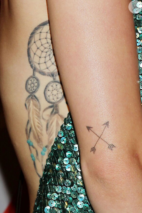 Miley Cyrus usa vestido decotado e deixa suas tatuagens à mostra