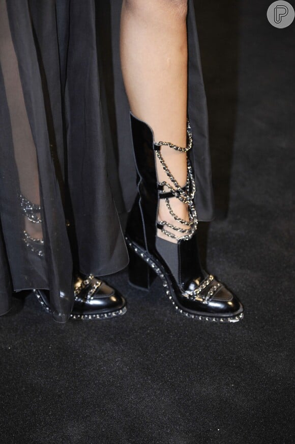 Os detalhes da peça nos pés de Izabel Goulart: a bota tem textura envernizada com as clássicas correntes presentes também nas bolsas