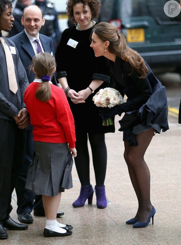 Ao conversar com uma menina, a saia de Kate Middleton começou a levantar por causa do vento