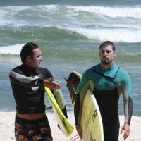 Cauã Reymond surfa com amigo na praia da Barra da Tijuca, no Rio