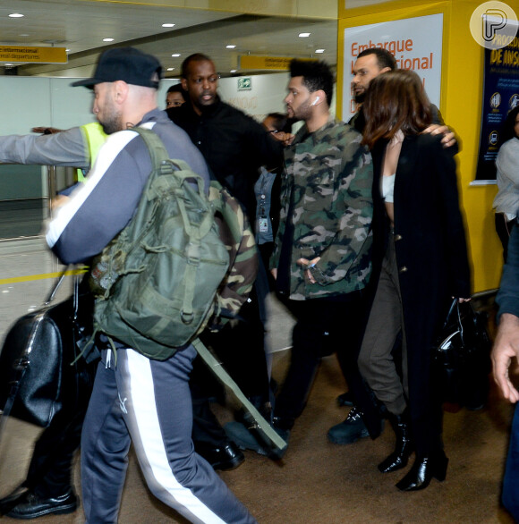 Selena Gomez e The Weeknd são escoltados por seguranças no embarque internacional do aeroporto de Guarulhos, em São Paulo, na madrugada desta segunda-feira, 27 de março de 2017