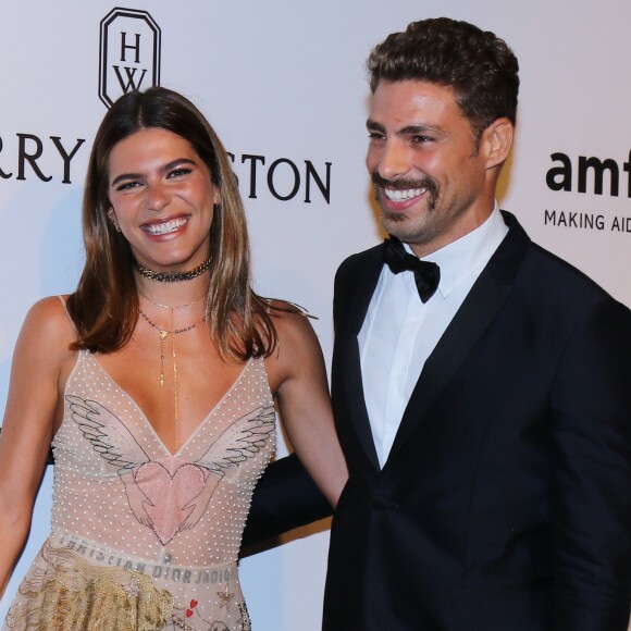 Cauã Reymond e Mariana Goldfarb posam sorridentes pelo tapede vermelho do baile amfAR