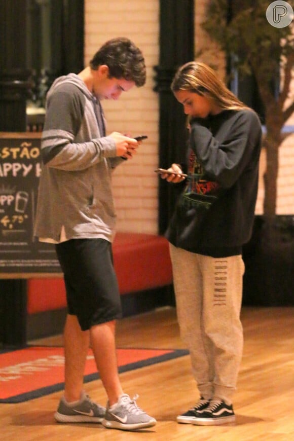 Felipe Ricca, filho de Adriana Esteves, e a namorada ficaram concentrados no celular durante passeio no shopping nesta quinta-feira, 4 de maio de 2017