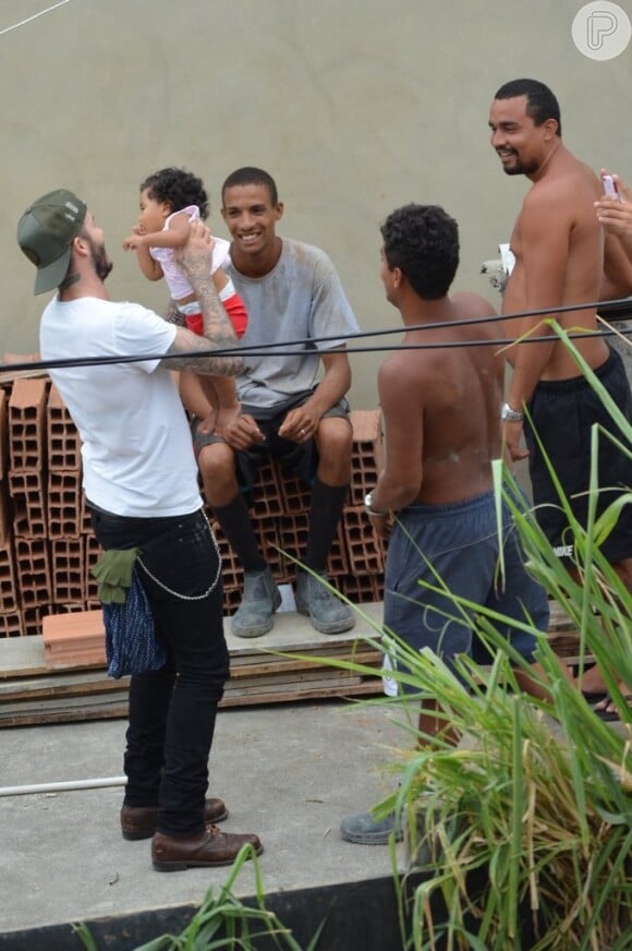 David Beckham aproveitou para visitar a comunidade do Vidigal, no Rio. Ele tirou fotos com fãs e pegou um bebê no colo