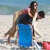 Isis Valverde se diverte ao pular no namorado, o modelo André Resende, em dia de praia