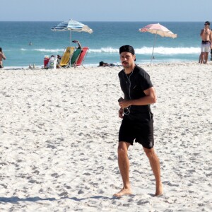 Cauã Reymond corre em praia da Barra da Tijuca, no Rio, com look total black