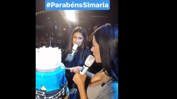 Simaria, dupla de Simone, distribui bolo ao festejar aniversário no palco. Vídeo