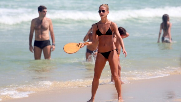 Em dia de sol, Fernanda de Freitas joga frescobol, surfa e namora na praia