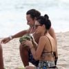 Isis Valverde bebe água de coco na praia em 6 de maio de 2014