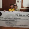 Daniele Winits posou sorridente segurando o cheque ao lado de uma criança