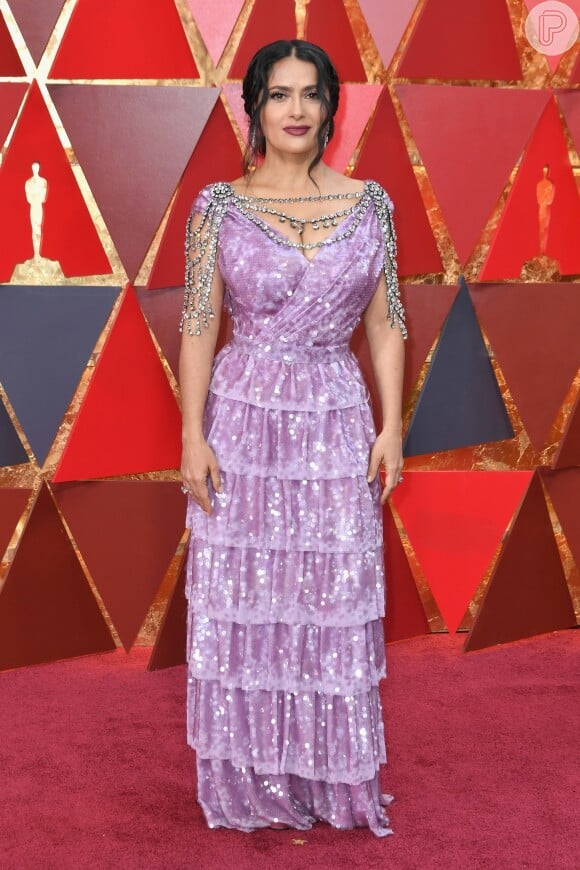 Salma Hayek usando um modelo Gucci lilás com babados, paetês e uma cascata de cristais no colo, ombro e costas na 90ª edição do Oscar