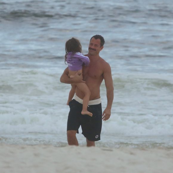 Malvino Salvador sorri ao carregar a filha Ayra quando saiu do mar