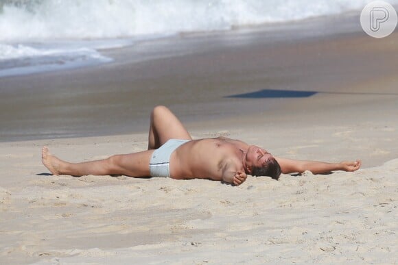 Marcos Frota deita na areia após mergulho no mar